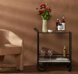 bar cart with bottles and glasses next to chair